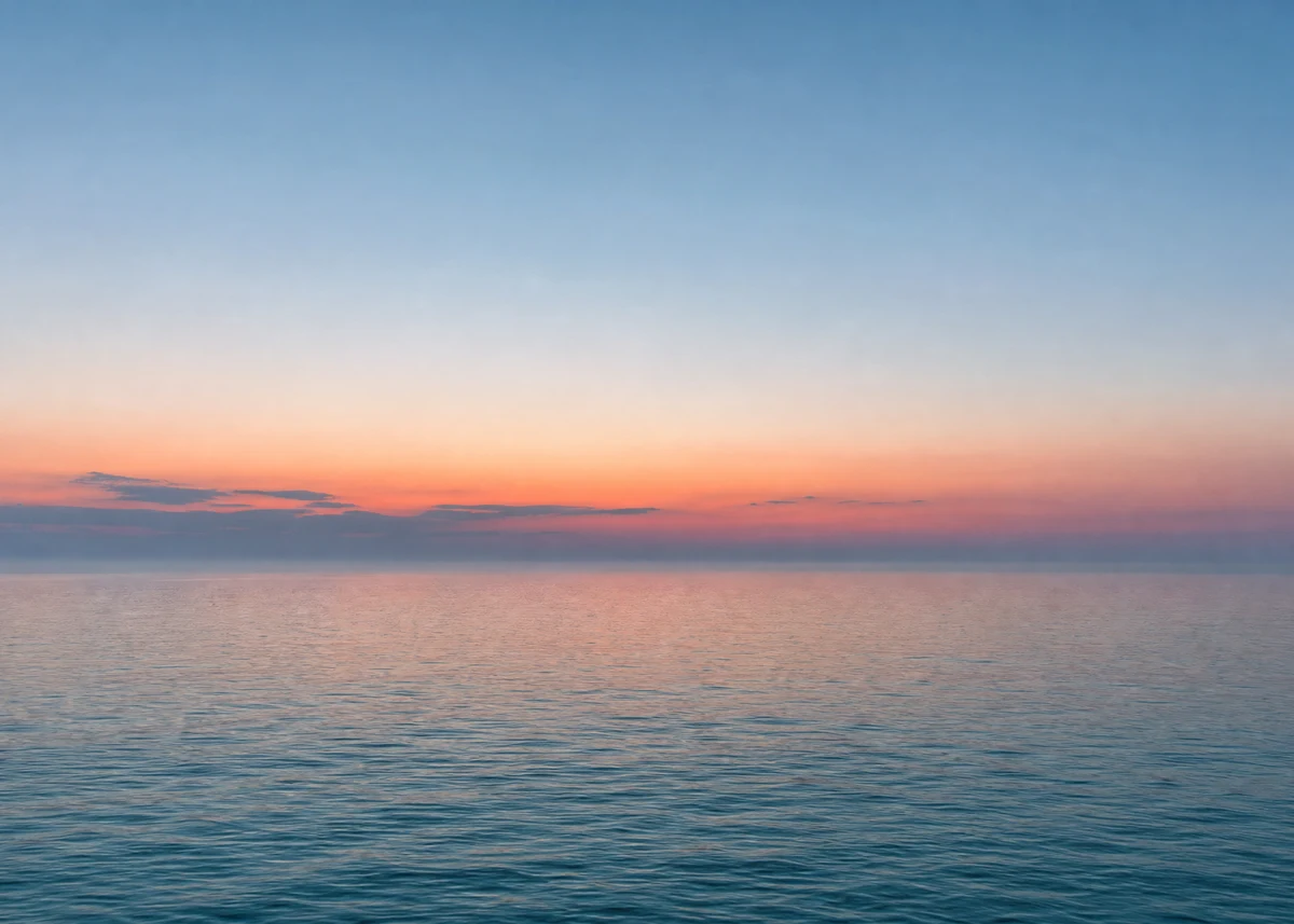 Mar en calma al amanecer con el horizonte en tonos rosados